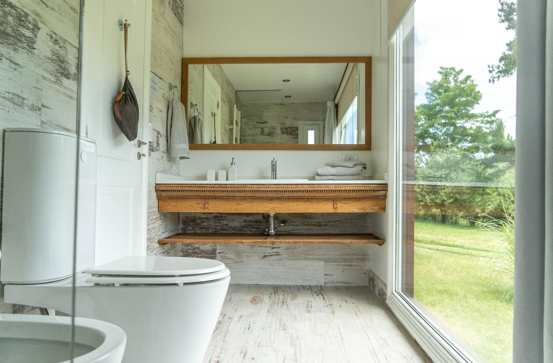 Baño en La Aguada Suite con espejo grande, vanitory y ventanal con vista al jardín en El Bolsón Baño en La Aguada Suite con espejo grande, vanitory y ventanal con vista al jardín en El Bolsón