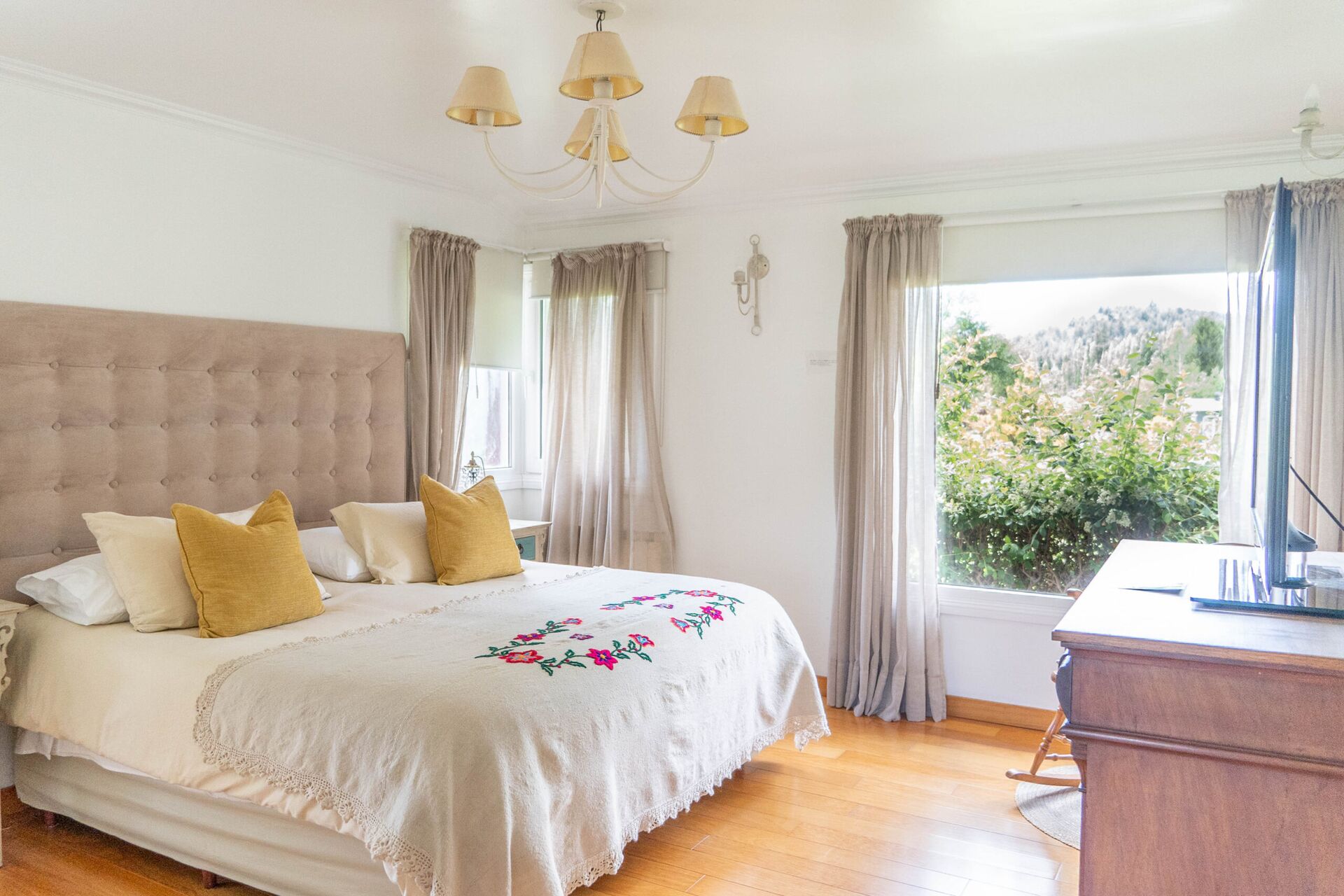 Dormitorio luminoso en La Aguada Suite, El Bolsón, con cama amplia, almohadones, TV y vista al jardín Dormitorio luminoso en La Aguada Suite, El Bolsón, con cama amplia, almohadones, TV y vista al jardín
