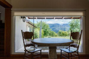 Mesa junto a ventanal con vista al jardín y montañas en La Aguada Suite, El Bolsón, Patagonia.